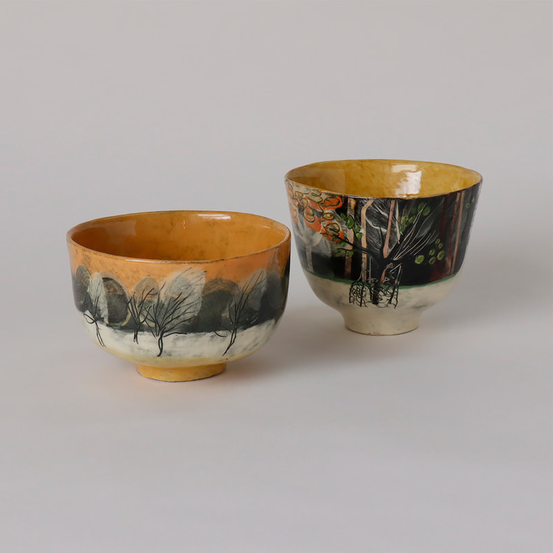 two hand built ceramic chawans painted with slips, depicting trees
